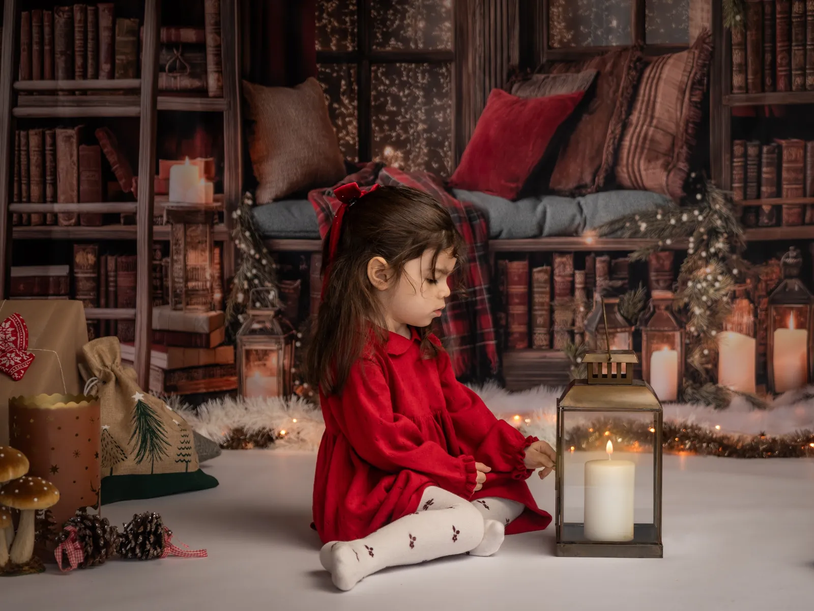 Décor de Noël rouge et vert au studio à Aix-en-Provence : étagères de livres, coussins rouges, lanternes et bougies