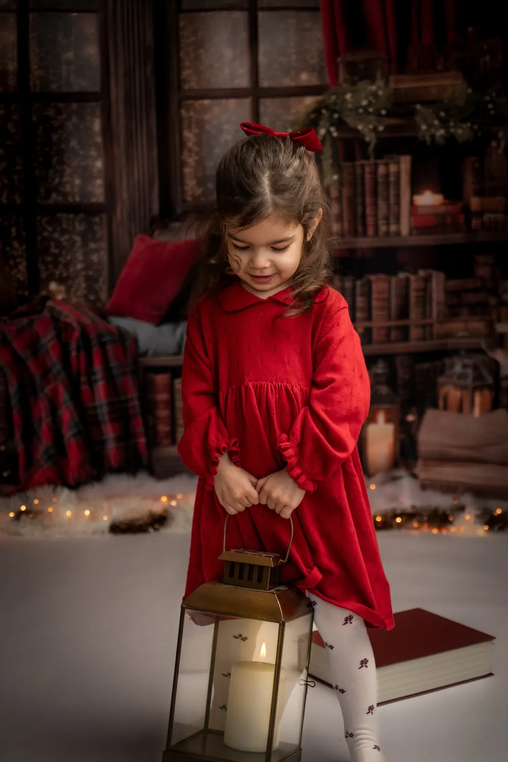 Petite fille en robe rouge debout avec une lanterne, décor de Noël au studio à Aix-en-Provence