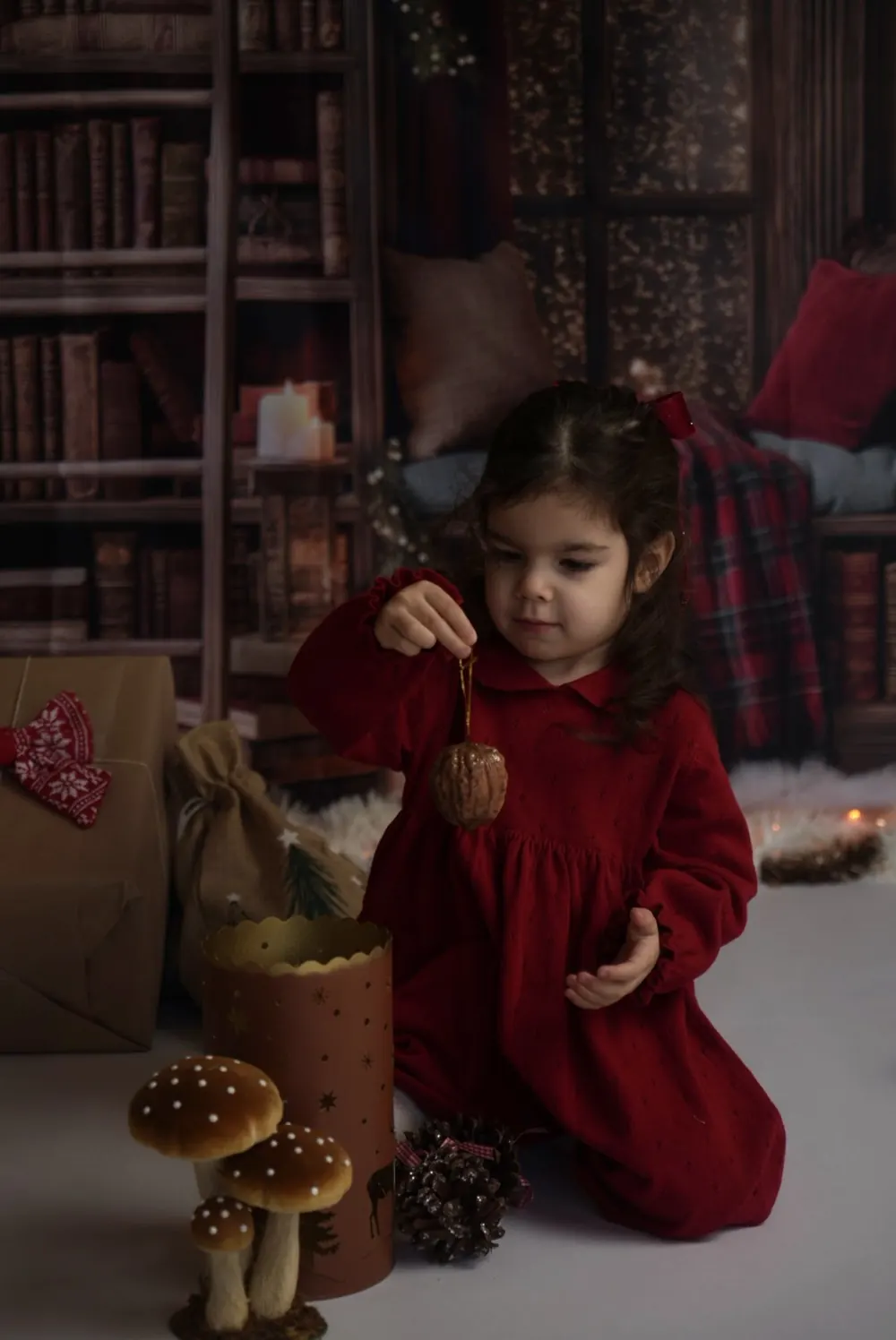 Petite fille à genoux avec une décoration de Noël, champignons et pommes de pin, studio à Aix-en-Provence